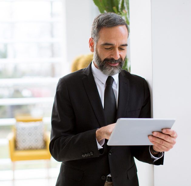 Handsome mature businessman with tablet in the office working, r Handsome mature businessman with digital tablet in the office working, reading or searching something
