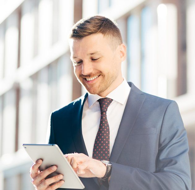 Outdoor shot of prosperous delighted male entrepreneur searches successful ideas for business in internet, uses modern tablet computer, dressed in formal suit. Male economist with digital device Outdoor shot of prosperous delighted male entrepreneur searches successful ideas for business in internet, uses modern tablet computer, dressed in formal suit. Male economist with digital device